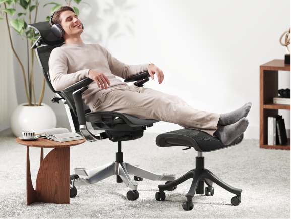 Man reclining in an office chair with feet elevated on the CF5 ergonomic footrest while relaxing