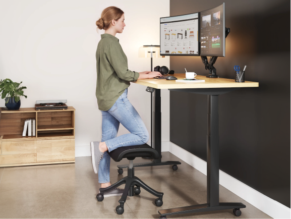 Woman standing at a desk with one foot resting on the CF5 ergonomic footrest for support