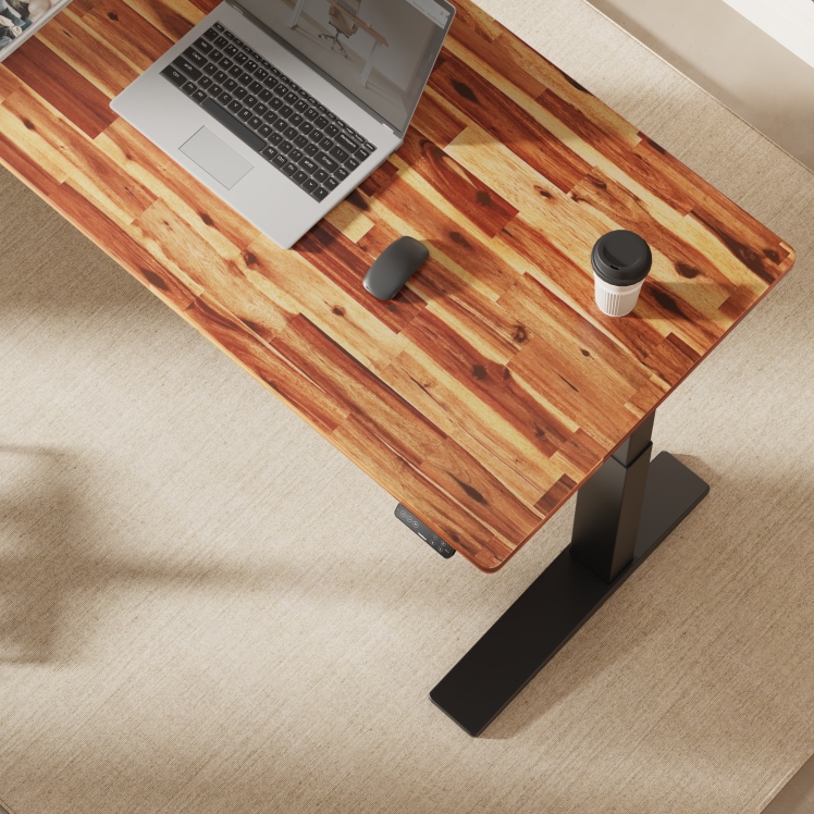 Top-down view of a solid acacia wood electric standing desk with a laptop, mouse, and coffee cup