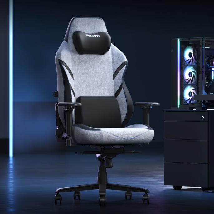 The GC7 ergonomic gaming chair sits in a dark, neon-lit gaming room next to a gaming desk.
