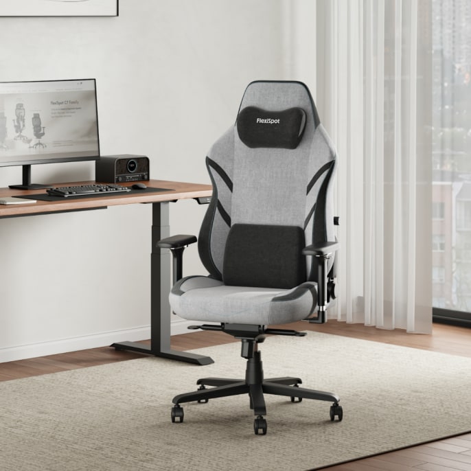 The GC7 ergonomic gaming chair is placed at a standing desk in a bright, modern home office.