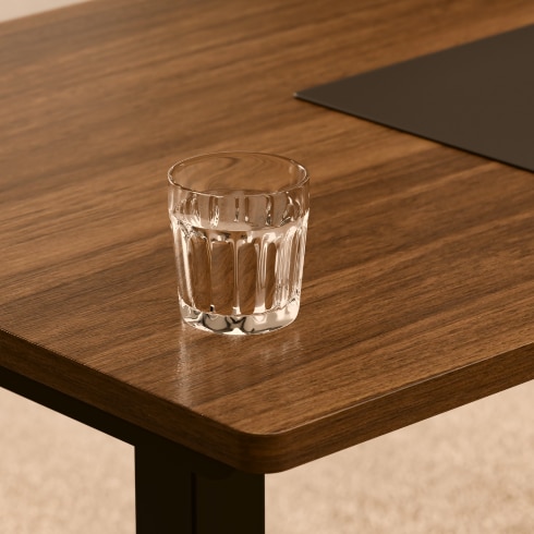 Tabletop appearance under warm light, displaying warm surface texture with glass cup reference