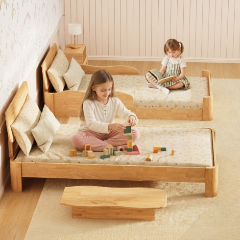 Two children of different ages reading and playing on two different bed styles designed for their respective age groups.