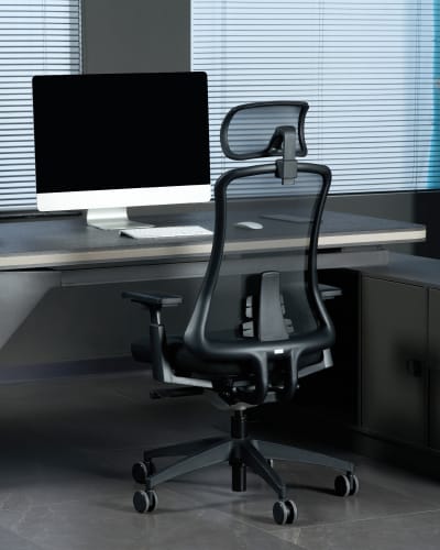 A modern office setup featuring a black ergonomic chair in front of a sleek desk with a blank computer monitor.