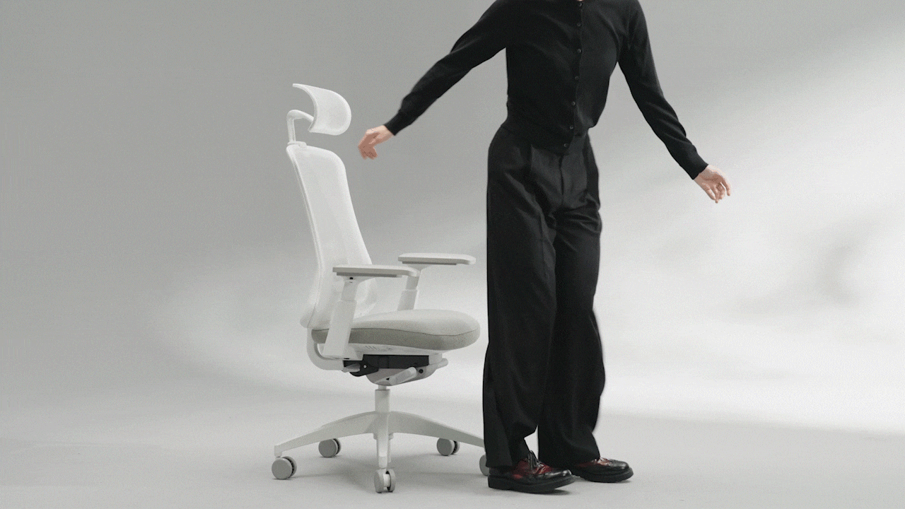 A person in black clothing demonstrates a modern white office chair, showcasing its features and design.